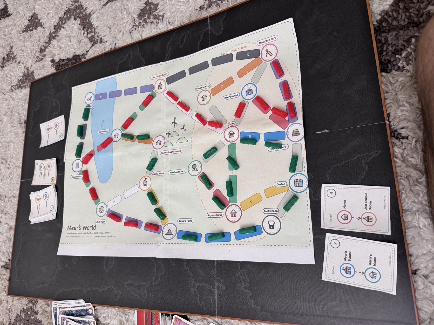 A taped Mapventure board with colorful route pieces and printed adventure cards during play.