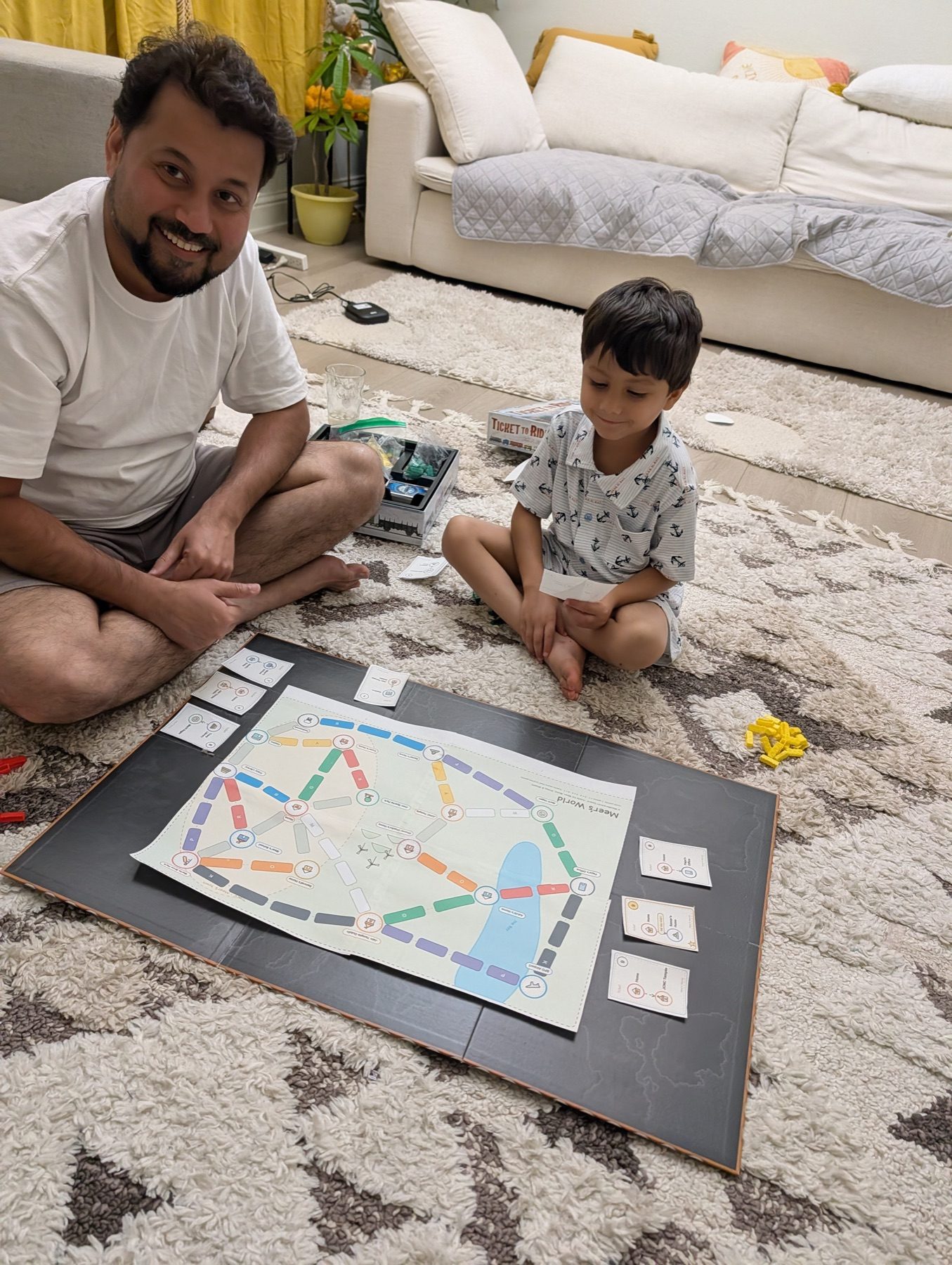 Meer and Daddy sitting beside a printed Mapventure board during a family playtest.